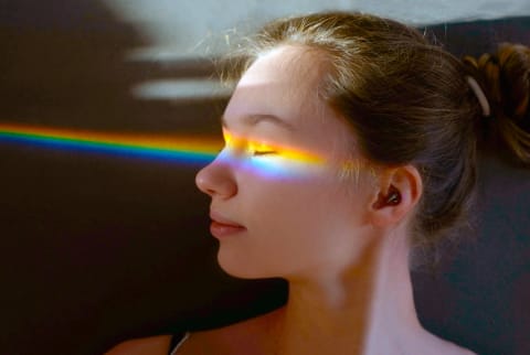 girl with rainbow light spectrum hitting her face