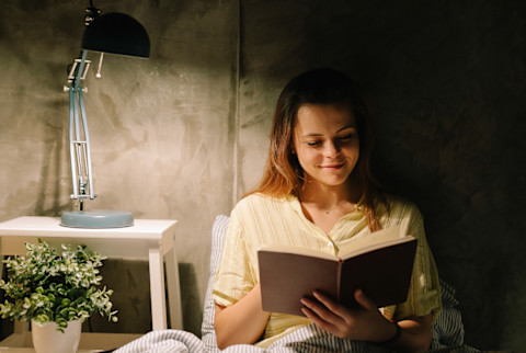 Young Woman Reading A Book In Bed Young Woman Reading A Book In Bed