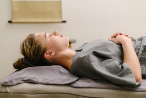 Young beautiful woman having acupuncture procedure by traditional chinese medicine doctor