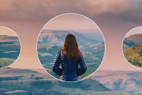 A woman on a walk in nature stops to look at a dramatic sunset view