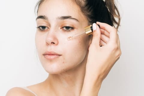 Young woman applying a serum to her face