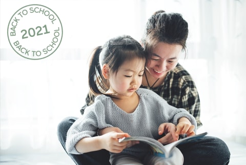 Young Asian mother and her toddler cute girl reading books at home