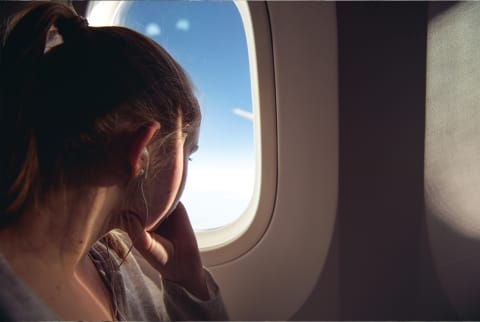 woman looking out window on plane