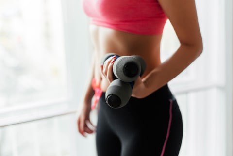 Cropped image of a woman holding fitness dumbbells.