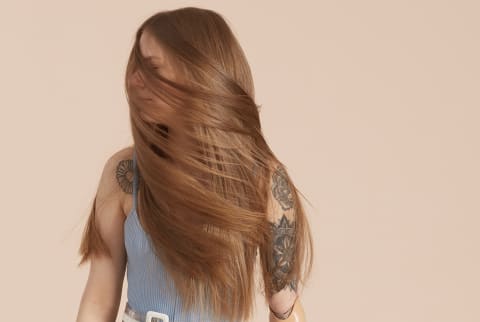 Woman with long shiny hair concealing her face