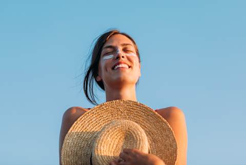 Woman with sunscreen on nose and cheeks basks in the sun