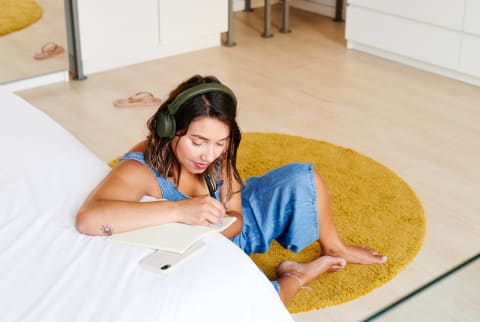 Woman Writing In A Notebook And Listening To Music