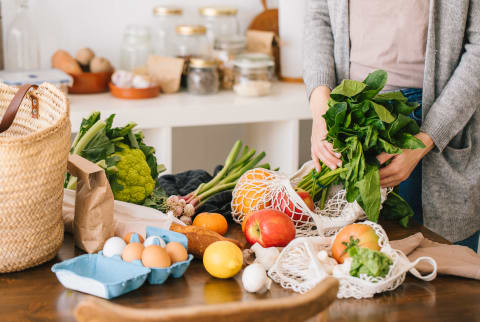 Fresh Fruits And Vegetables In Reusable Bags On Kitchen Table