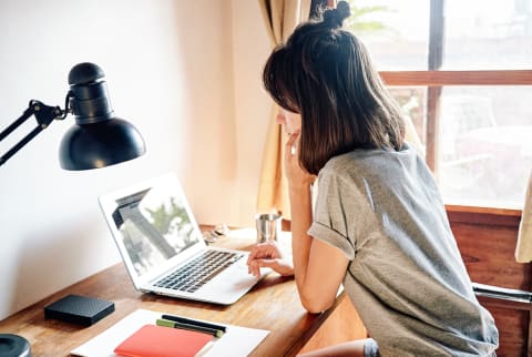 Young woman working on laptop on the desk at her home