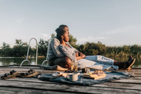 Couple Enjoying an Outdoor Picnic By a River At Sunset