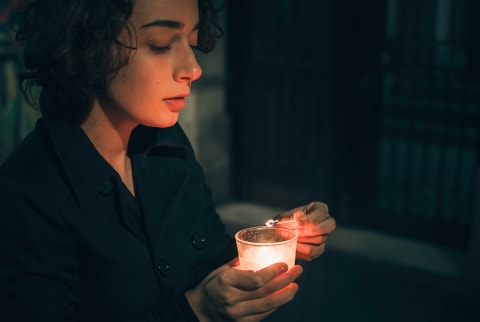 Woman Lighting A Candle In The Darkness