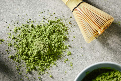 Top view of green tea powder and bamboo whisk on table