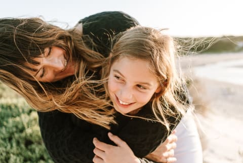 Mother Hugging Her Daughter on a Windy Day At The Beach