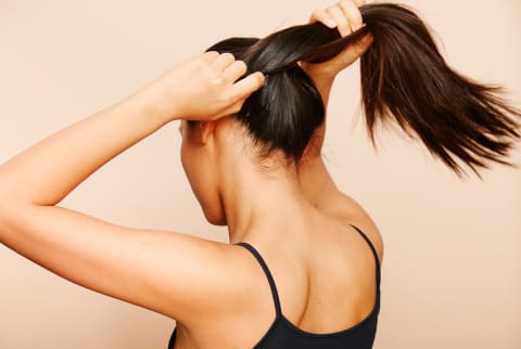 Woman Tying Her Hair in a Ponytailq