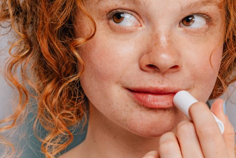 Young Womanl applying lip balm