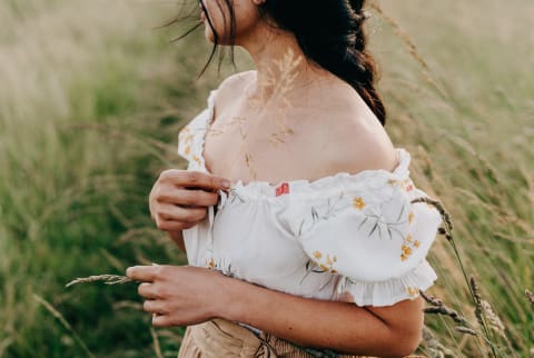 Woman standing in a grassy field and enjoying the late day summer weather Woman standing in a grassy field and enjoying the late day summer weather