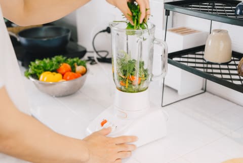 Someone Adding Greens into a Blender to Make a Smoothie