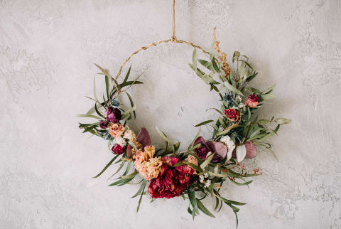 Summer Wreath of Dried Flowers and Greens Hanging on a Wall
