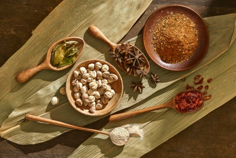 Various herbs and spices on spoons and plates on wooden background