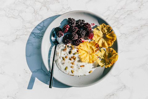 Yogurt with dried pineapple flowers, frozen blackberries and keto granola