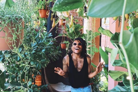 person smiling in plant shop filled with greenery