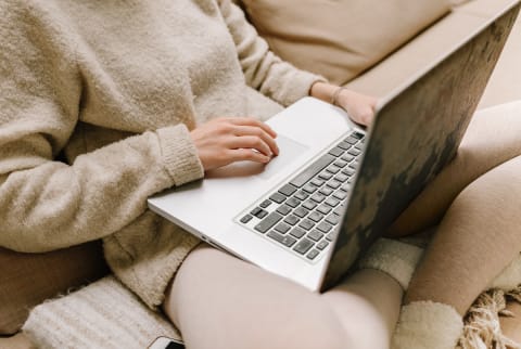 Anonymous Woman In Sweater Using Laptop On Sofa