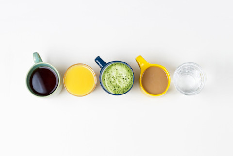 Coffee tea and other drinks in colorful cups on a white background, top view Coffee tea and other drinks in colorful cups on a white background, top view