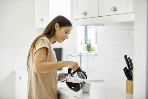 Woman Pouring Coffee into Cup in Her Kitchen