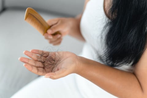 Woman experiencing hair shedding after combing hair