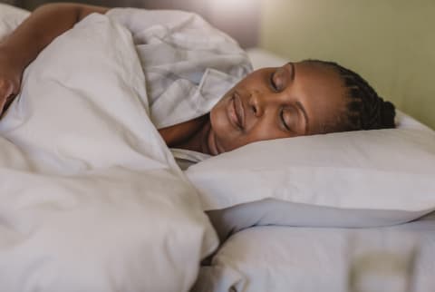 African American woman sleeping soundly in her bed at home stock photo