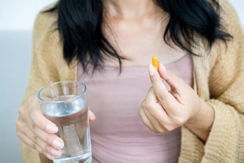 Woman taking a supplement with water