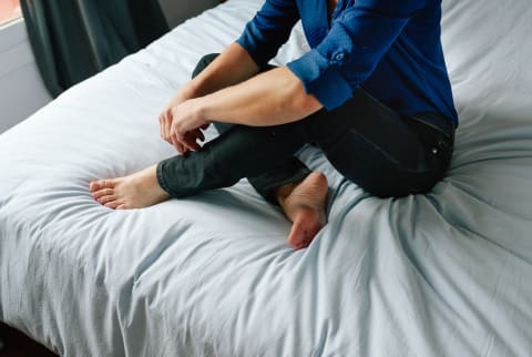 Cropped Photo of a Woman Sitting on a Bed