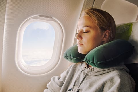 Woman Asleep on an Airplane with a Neck Pillow