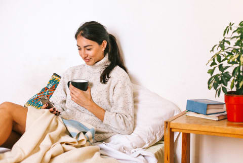 Woman Looking at Her Phone and Drinking Coffee on a Cozy Afternoon