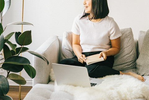 Woman Smiling on a Couch at Home with Her Laptop