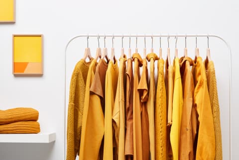 Rack of bright yellow-colored clothing on rack in white wardrobe room