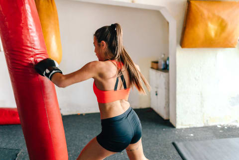 Woman Kickboxing and Punching a Weighted Bag