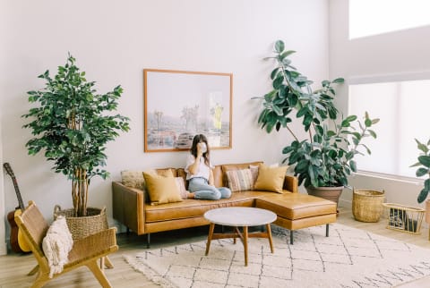 Woman Sitting on a Couch Drinking Coffee in Her Clean, Brightly Lit Living Room