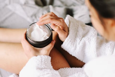 Closeup Of A Woman In Bathrobe Using A Cream