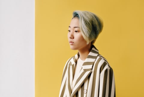 Portrait of young woman in 20s wearing stylish outfit standing against white and yellow wall background