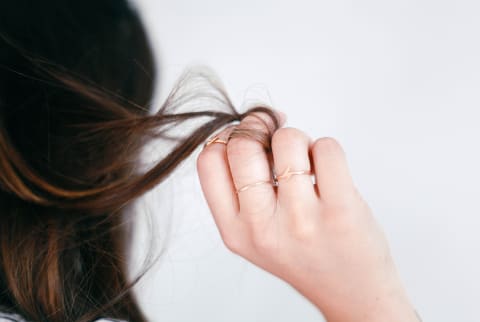 Woman Holding A Piece Of Her Hair In Her Hand