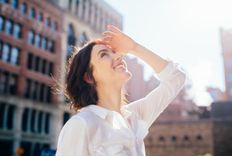 Woman in a White Shirt Looking Up in a City