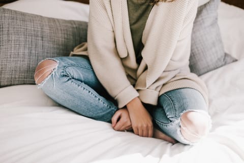 Unrecognizable Woman Sitting Cross Legged on Bed