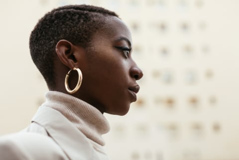 Thoughtful Young Woman Wearing a Turtleneck, Blazer, and Gold Earrings