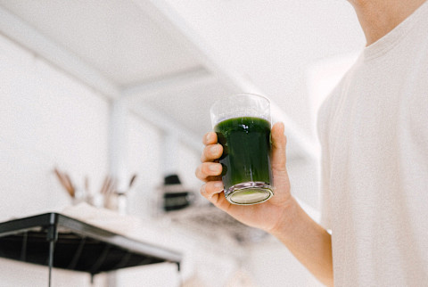 Man Holding a Glass of Dark Green Juice