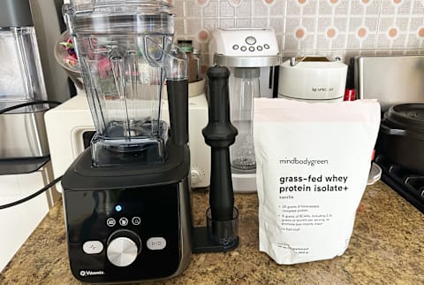 Image of Vitamix Blender next to bag of mindbodygreen protein powder in vanilla Image of Vitamix Blender next to bag of mindbodygreen protein powder in vanilla