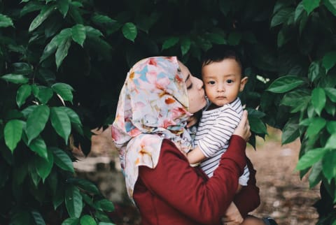 woman wearing hijab kissing baby