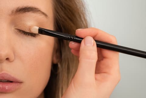 woman applying eyeshadow with makeup brush