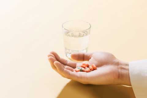 Handfull of pills with a glass of water