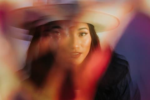 Woman looking straight through camera with color and light refracting